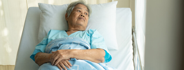 Asian grandma have alzheimer's on the bed looking away to window