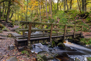 Fototapeta na wymiar Wooden footbridge over Burbage Brook in the wonderful Padley Gorge near Grindleford, Peak District National Park, Derbyshire