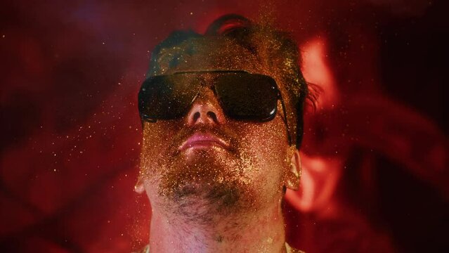 Comical video funny person.Blowing powder.Serenity control stability positive emotion guy in sunglasses.Blow smoke spray gold dust in slow motion 1000fps.Calmness relax chill face man in gold glitter