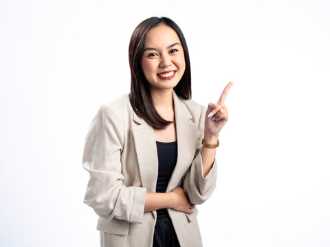 A portrait of an Indonesian Asian woman wearing a cream-colored blazer, posing as if having an idea with her index finger pointing upward. Isolated against a white background.