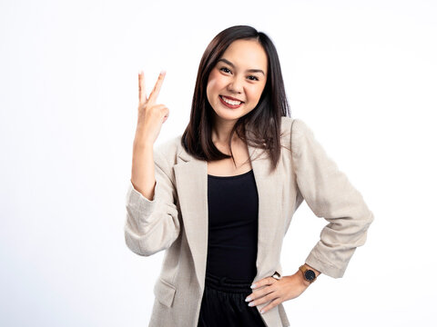 A portrait of an Indonesian Asian woman wearing a cream-colored blazer, posing with two fingers. Isolated against a white background.