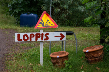 Hand-painted sign with arrow and the text flea market in Swedish (= loppis), pointing to a typical...