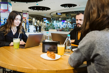 A group of adults and a child working from mall while having a drink