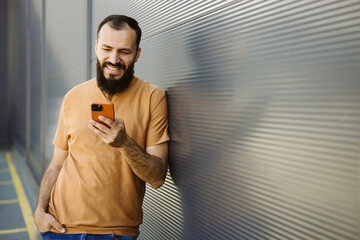 Caucasian bearded man smiling using smartphone