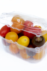 Containers plastic transparency with, Different sorts of tomatoes isolated on white background. Fresh, ripe type of small and round cocktail tomatoes, of red, yellow and orange color.