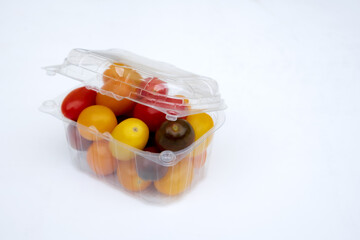 Containers plastic transparency with, Different sorts of tomatoes isolated on white background. Fresh, ripe type of small and round cocktail tomatoes, of red, yellow and orange color.
