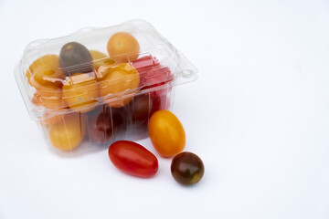 Containers plastic transparency with, Different sorts of tomatoes isolated on white background. Fresh, ripe type of small and round cocktail tomatoes, of red, yellow and orange color.