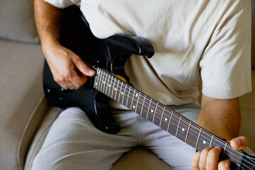 Fototapeta premium A man plays an electric guitar at home, online training, internet blog. No face