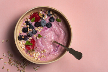 Homemade antioxidant summer fruits oatmeal on light pink background