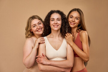 Diverse beauty. Charming ladies with curly, straight and short hair standing closely and smiling...