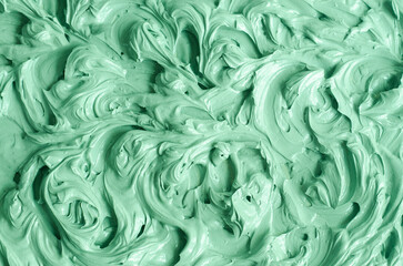 Green bentonite facial clay (alginate mask, face cream, body wrap) texture close up, selective focus. Abstract background with swirl brush strokes.