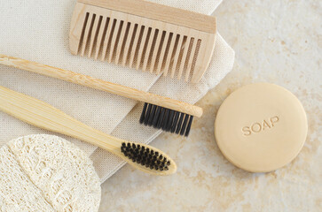 Bar of soap (solid shampoo), bamboo toothbrushes, wooden hairbrush (comb) and loofah sponge. Eco friendly toiletries set. Natural beauty treatment, skin care or zero waste concept. Top view.