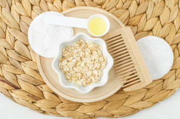 Small white plate with oatmeal and wooden hairbrush. Homemade hair or face mask, natural beauty treatment and spa recipe. Top view