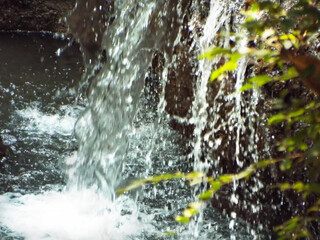 Waterfall pouring into a pond. Shiny splashes close up