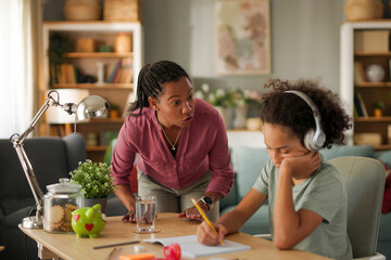 Displeased mother scolding her teenage son while doing homework at home