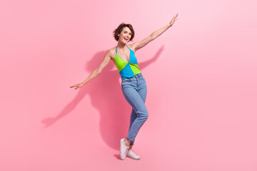 Fototapeta na wymiar Full body cadre of funky girl look like she flying airplane hands wear denim jeans with green blue top isolated on pink color background
