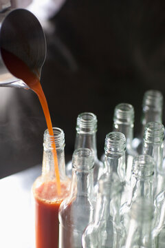 Tomato sauce being poured into a glass bottle

