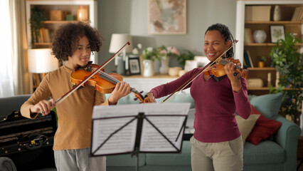 Mother and teenage boy playing violins at home