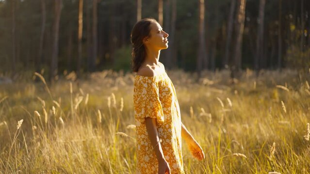 Beautiful Smiling Young brunette Woman wearing yellow sundress with perfect tanned Skin relaxing in forest. Happy girl walking in park. cheerful stylish girl in dress outdoors in nature
