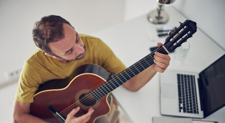 Obraz premium Man playing acoustic guitar at home.