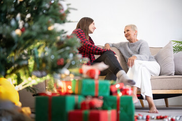 Obraz na płótnie Canvas Senior woman with adult daughter enjoying time at home on Christmas eve