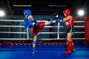 Competitive little athletic boys, children having boxing match in ring at gym. Nimble boy striking...