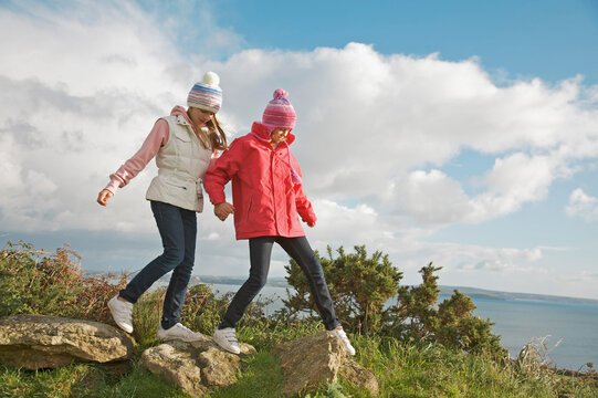 Two young girls walking on top of a cliff
