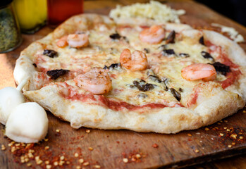 Traditional homemade Italian pizza with tomato, cheese, shrimps and black olives. Mozzarella. Olive oil. Food photography.