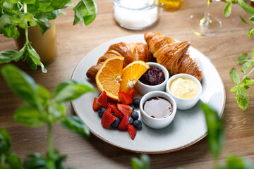 French breakfast set, top view. Croissants, fresh fruits, butter and jam, on a white plate, selective focus.