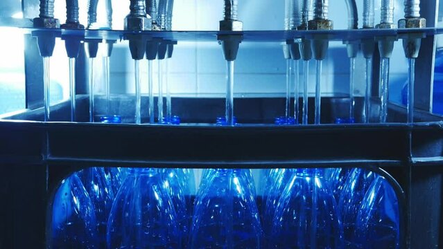 The process of filling clean drinking water into blue water bottles by an automatic drinking water filling machine in a drinking water production factory.