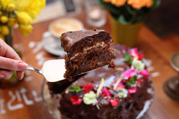 Taking a piece of chocolate cake by silver cake serving spatula, selective focus, close-up, with blurred background