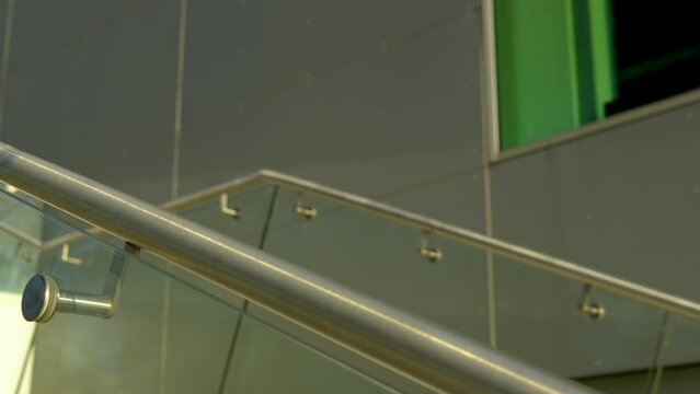 Close-up of modern stainless steel banister with glass panels on a stairway.