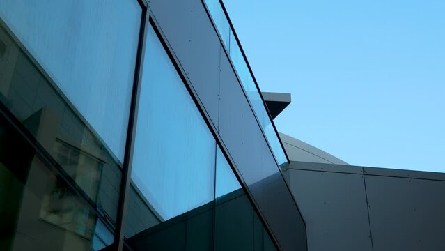 Modern architectural detail with angled glass facade against sky.
