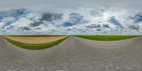 spherical 360 hdri panorama on old asphalt road among fields with clouds and sun on blue sky in...