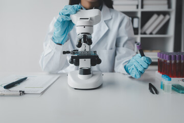 A chemist is using a microscope to search for chemicals from blood in a test tube, A scientific experiment is searching for biological answers in a laboratory, laboratory idea.