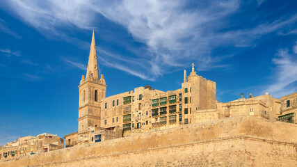 An old sandstone church and houses in Valetta, Malta, on a bright day