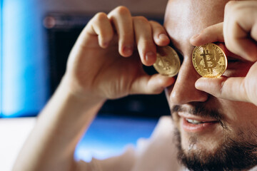 Man trader holding cryptocurrancy coins by his eyes
