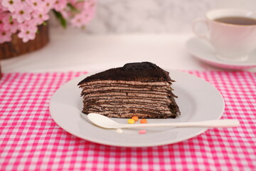 Piece of homemade chocolate crepes cake on a white plate
