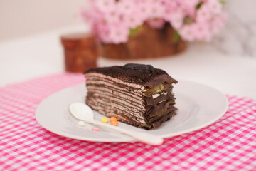 Piece of homemade chocolate crepes cake on a white plate