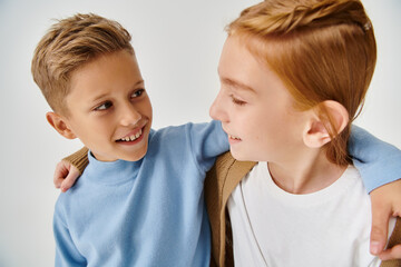 cute preteen children in trendy casual attires hugging and smiling at each other, fashion concept