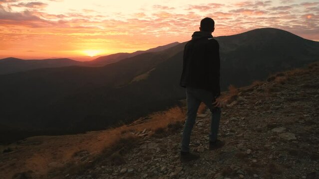 Ukrainian young man traveler walks along the most beautiful high mountain road in Romania Transalpina highway at sunset. Transalpina, Carpathian mountains in Romania at sunrise