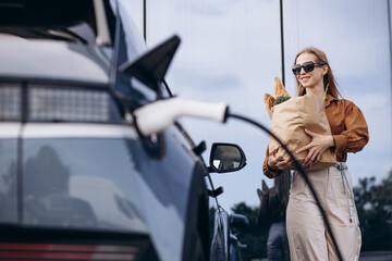 Woman doing grocery shopping while electric car charging