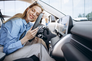 Woman smiling and holding steering wheel in her electric car