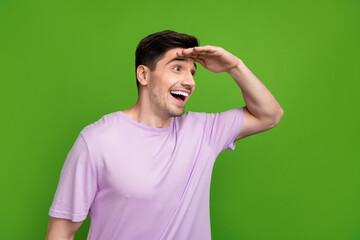 Fototapeta premium Photo of ecstatic man with brunet hair dressed purple t-shirt arm on forehead look at sale empty space isolated on green color background