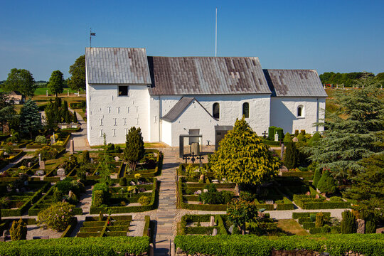 Path between small cemetery to the historic Jelling Church built around the year 1100 in Jelling village at North Jutland, Denmark. UNESCO World Heritage Site