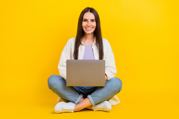 Full body photo of lovely positive lady sit floor crossed legs use wireless netbook isolated on yellow color background