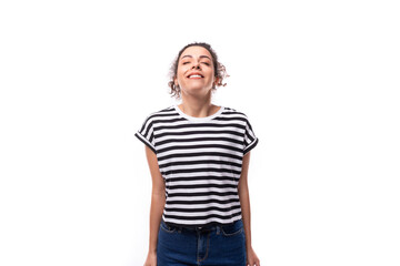 young joyful caucasian woman with curly black hair is dressed in a striped black and white t-shirt against the background with copy space