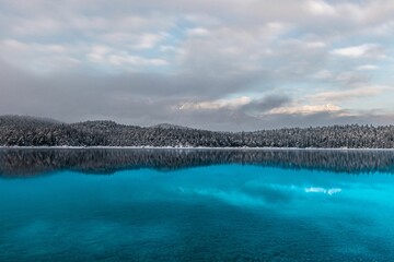 Scenic view of a lake against a forest covered with snow in winter