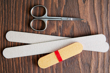 Flat lay with manicure tools, scissors and nail file on the rough wooden table. Cosmetics equip....