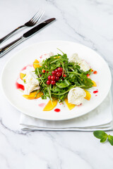 arugula salad with peach slices and red berries on a white plate top view